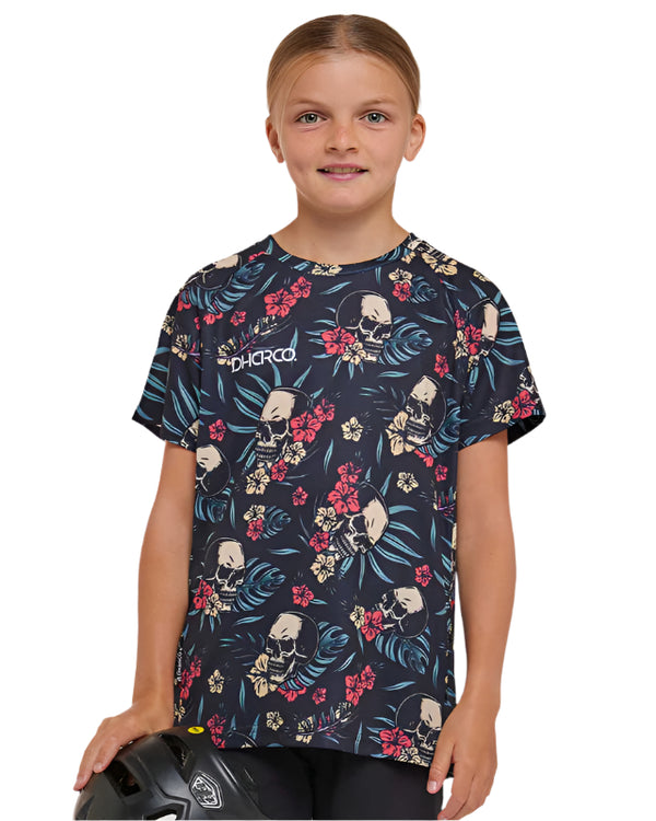 Child wearing a dark blue t-shirt with floral and skull pattern on a plain background